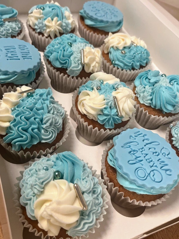 Box of cupcakes with blue and white buttercream swirls for a celebration