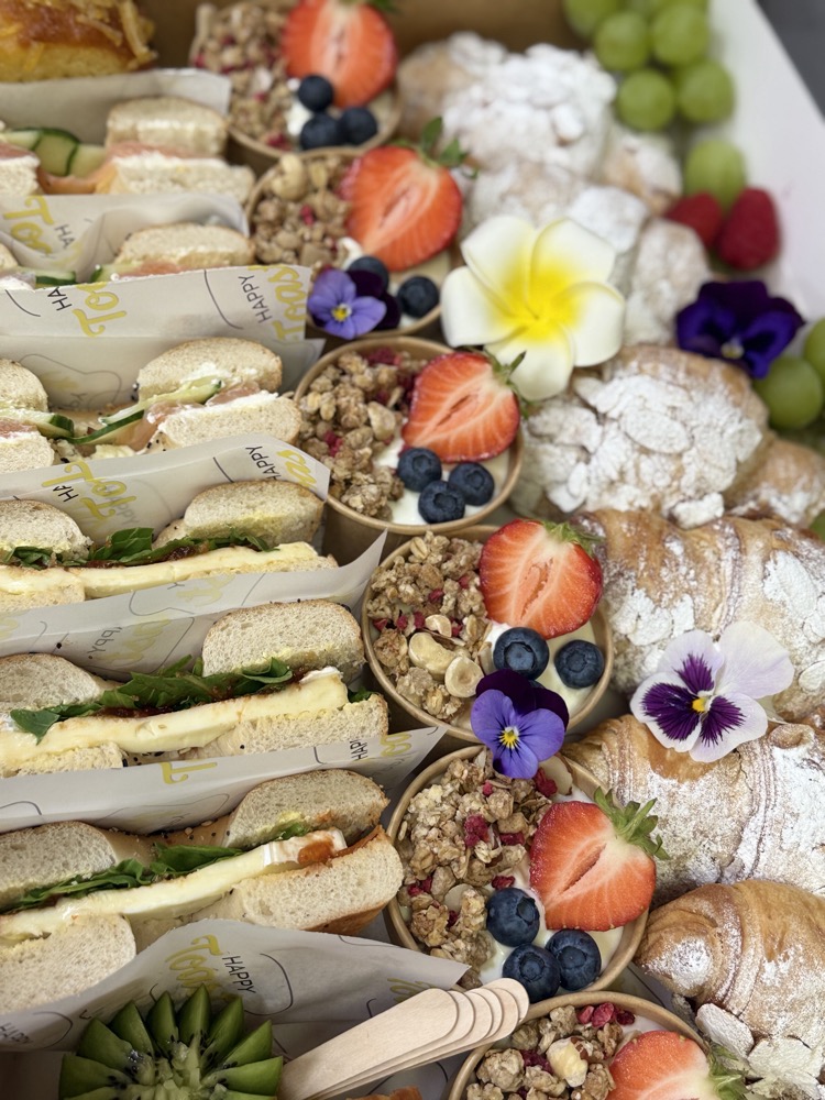 Brunch spread with sandwiches, fresh croissants, fruit and edible flowers