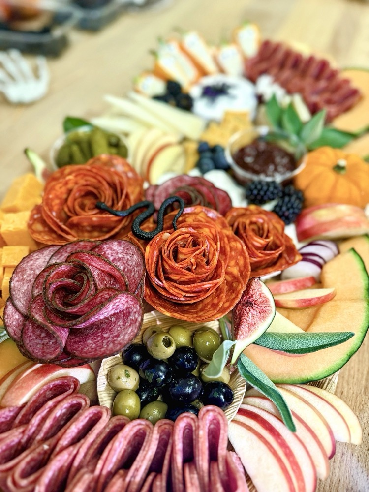 Charcuterie board with salami roses, cheese and fresh fruit