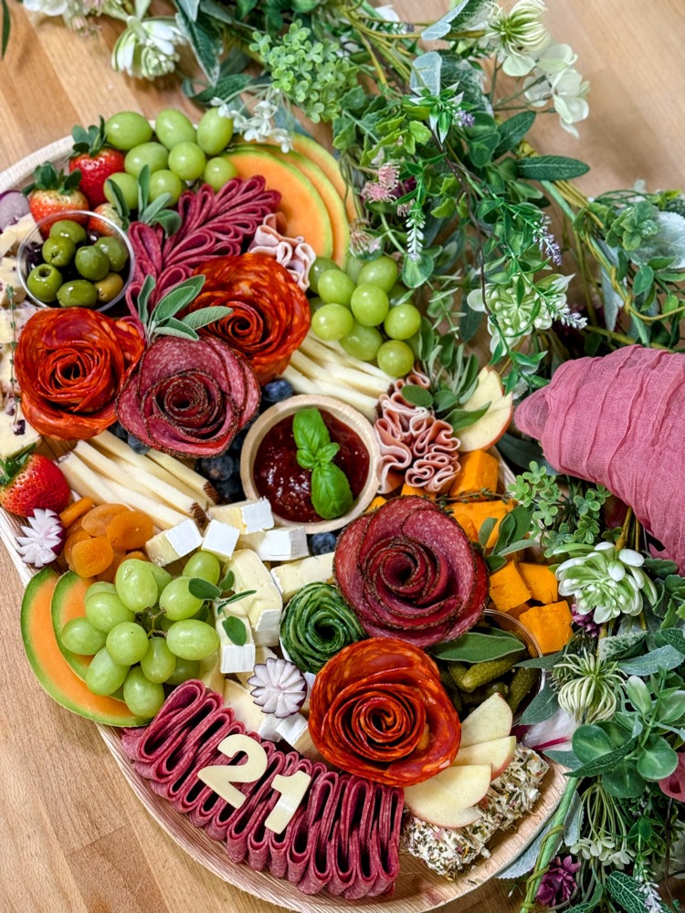 Charcuterie board with salami roses, cheese, fruit and fresh herbs