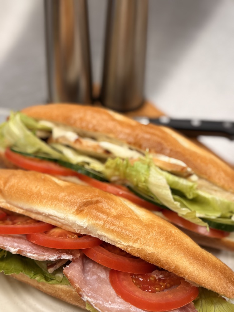 Close-up of a deli baguette sandwich with ham, tomato and salad