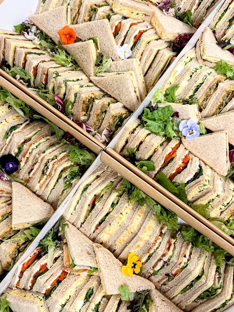 Platters of sandwich triangles garnished with edible flowers and salad