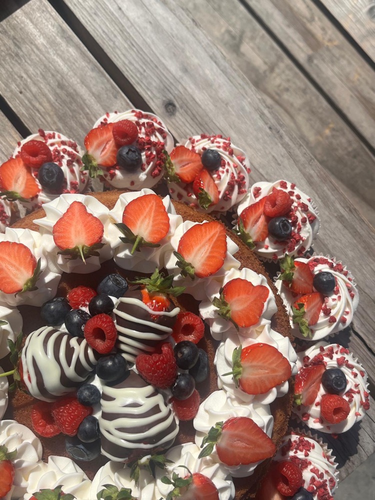 Cake topped with cream swirls, fresh strawberries and a chocolate-dipped strawberry