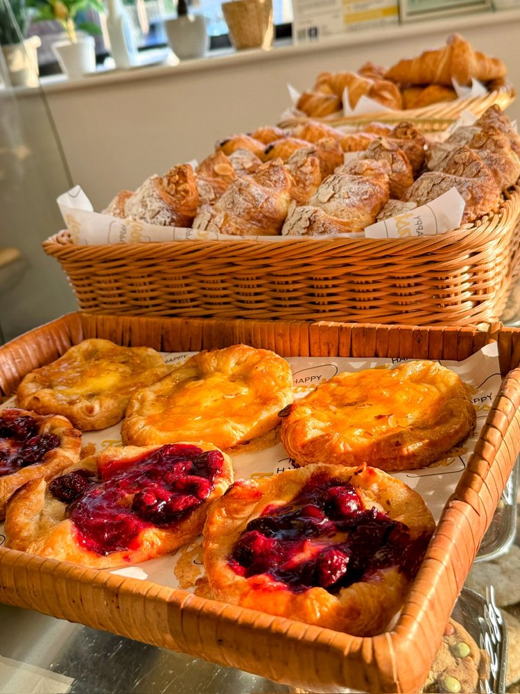 Baskets of croissants and trays of custard and berry Danish pastries on the counter