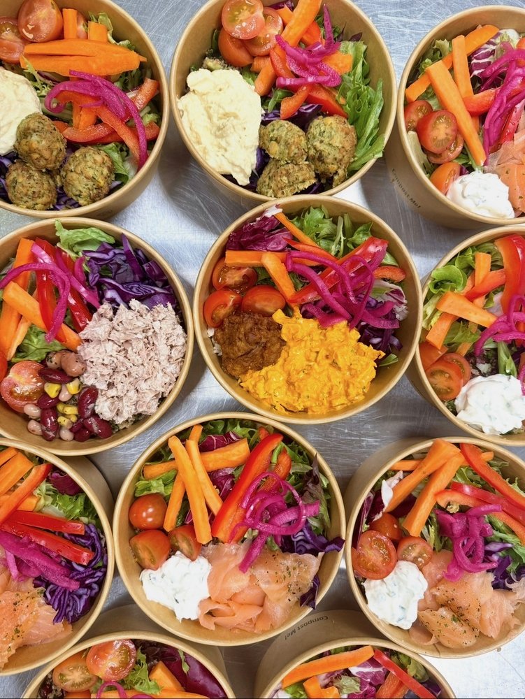 Salad bowls topped with falafel and hummus, tuna, coronation chicken and smoked salmon