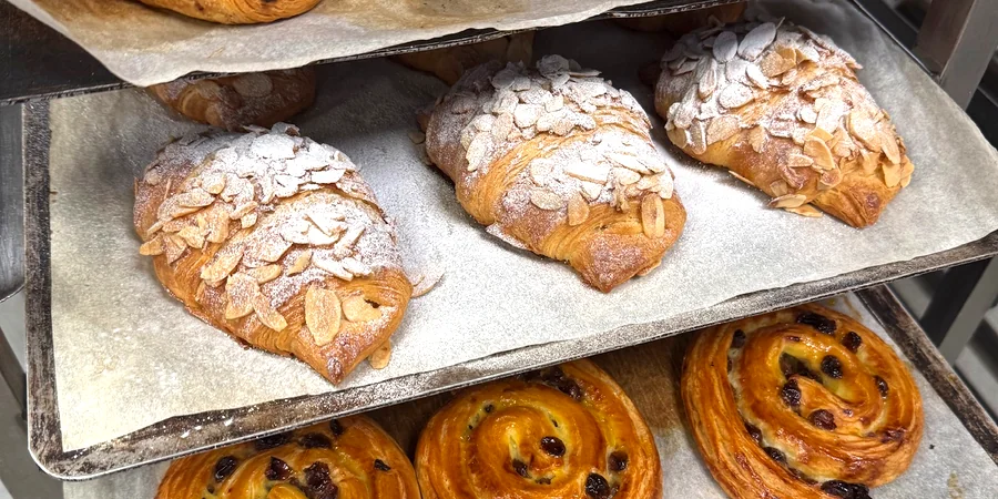 Almond croissants and pain aux raisins on bakery trays
